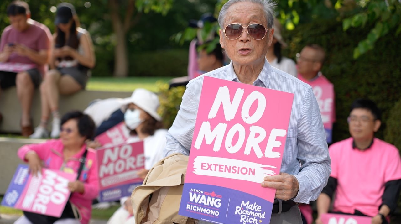 default-4458 Man holding a protest sign reading "No more extension." Other people holding protest signs are in the background.