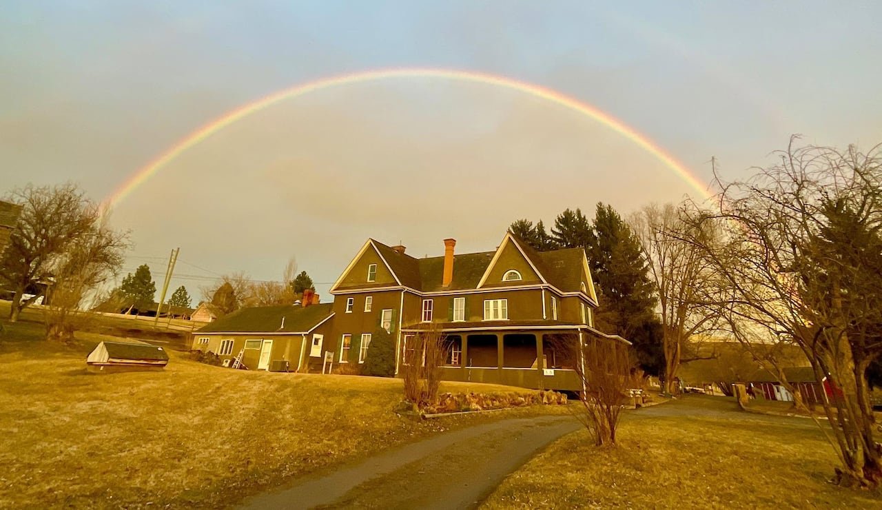 default-6207 A historic farmhouse with a rainbow over it.